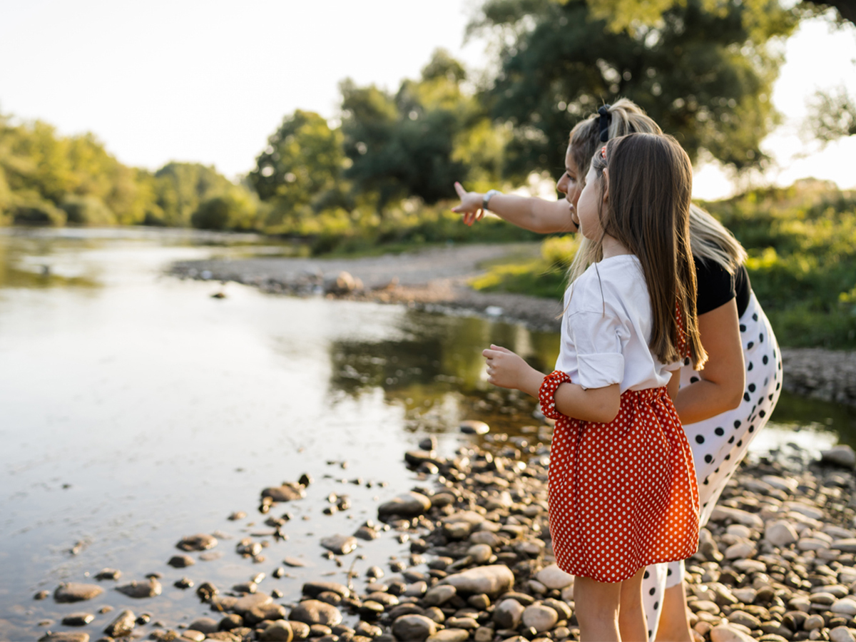 Neighbours and children clearing litter together along a sunlit riverbank