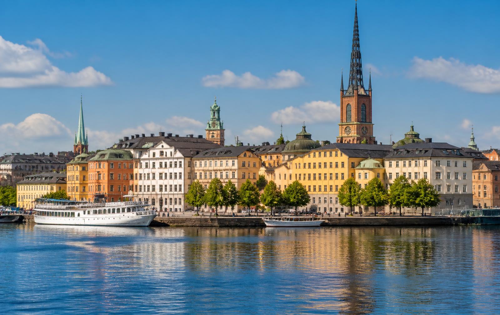 Stockholm waterfront in summer daylight, with historic buildings reflected in calm water
